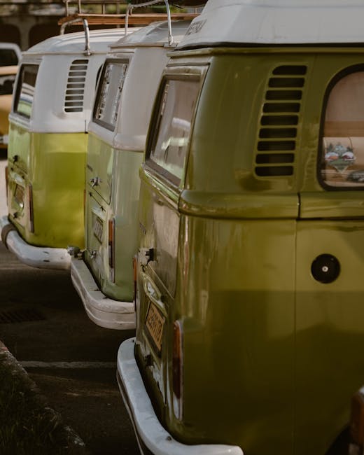 A large parking area filled with numerous white commercial vans arranged in evenly spaced rows, all featuring ribbed metal rooftops. The vans are parked close together on a paved surface, with some sh